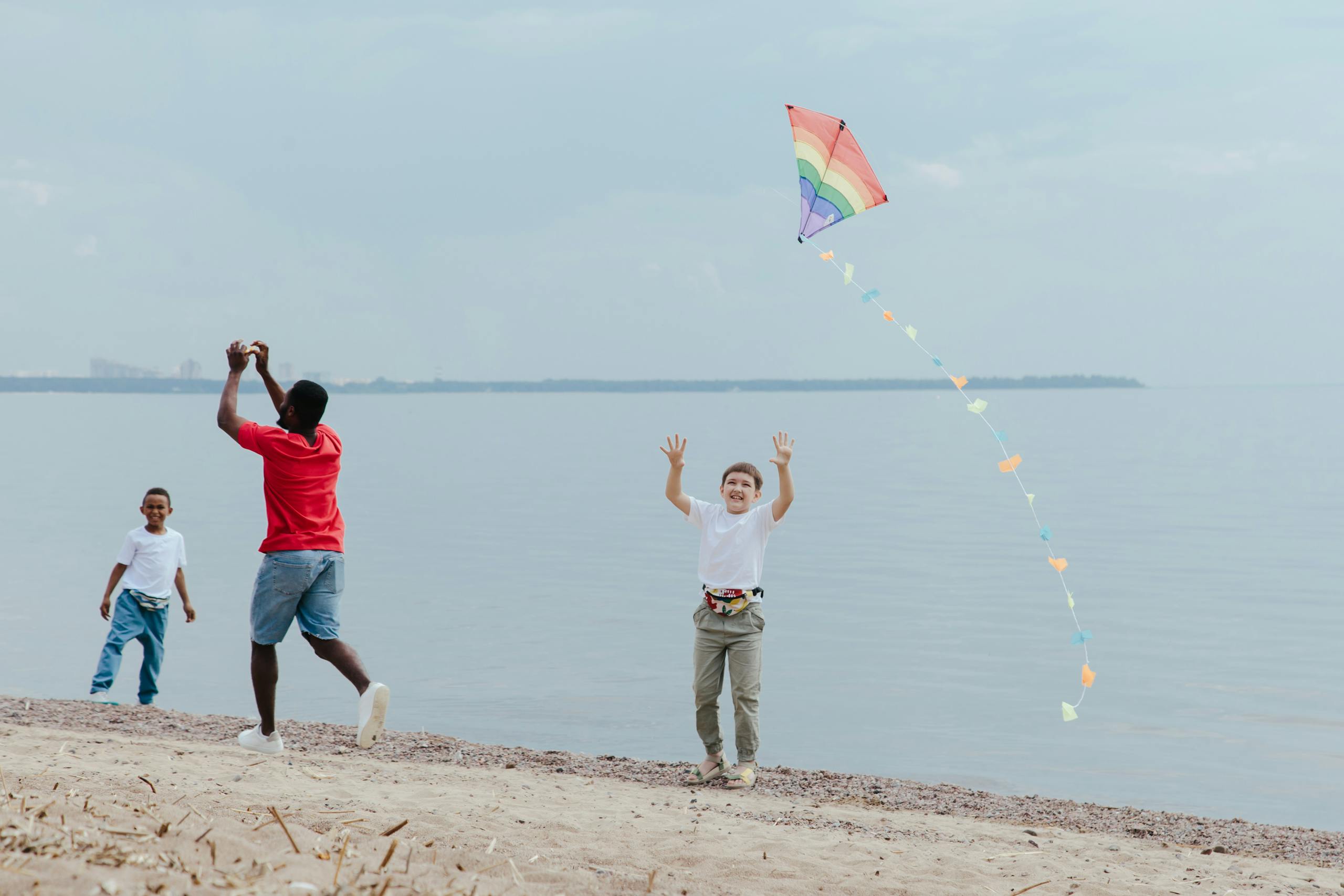 A Man and Two Boys Flying Kite by the Seashore